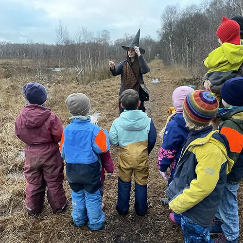 Die Moorhexe zeigt einer Gruppe von Kindern, was es im Dosenmoor zu entdecken gibt.